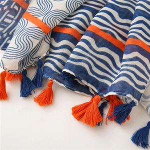 Détail d'écharpe en coton lin bohème avec motifs géométriques bleu orange et pompons