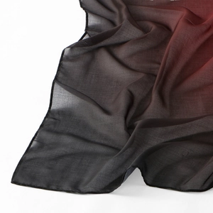 Detail of lightweight voile scarf with dark black to red gradient and sheer fabric texture