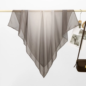 Close-up of gradient voile scarf in coffee brown hanging on a wooden rack detail