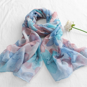 Close-up of lightweight floral voile scarf with blue and purple prints on white linen
