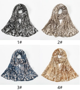 Detail view of four floral print scarves in marble tie-dye patterns and soft voile fabric