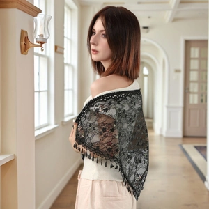 Elegant black lace shawl with tassel fringe details worn by a model in a bright setting
