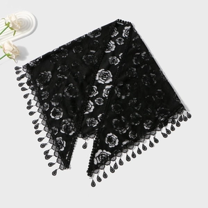 Detailed macro view of black lace shawl featuring rose patterns and tassel fringe drops