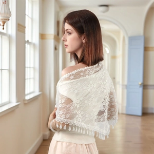 Detailed view of white floral lace shawl featuring elegant teardrop tassel trim and crochet texture