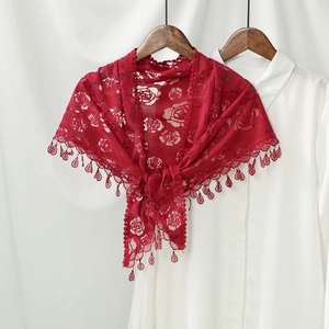 Macro detail of red lace shawl featuring intricate rose patterns and drop lace tassels