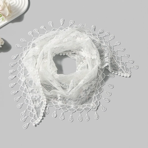 Detailed close-up view of white floral lace triangle scarf with elegant tassel trim