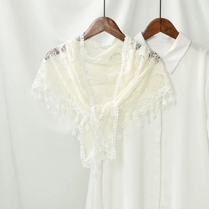 Close-up of rose embroidery and scalloped lace trim with droplet charms on a bridal shawl