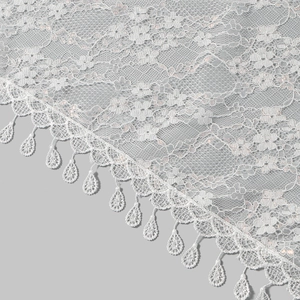 Macro detail of white lace shawl featuring delicate mesh and teardrop pendant fringe
