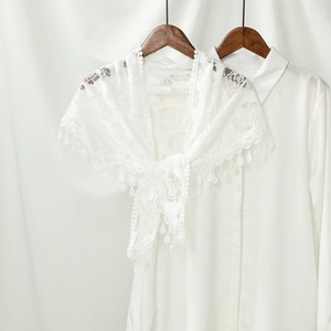 Close-up of white rose lace shawl with delicate scallop fringe detail on a wooden hanger