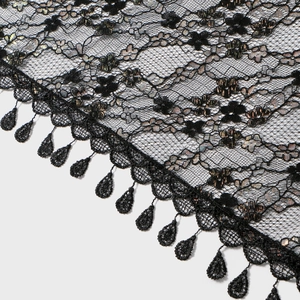 Detail of black lace shawl featuring floral embroidery and hanging droplet tassels