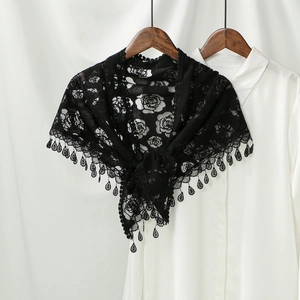 Close-up of black lace shawl with rose patterns and delicate teardrop pendant accents