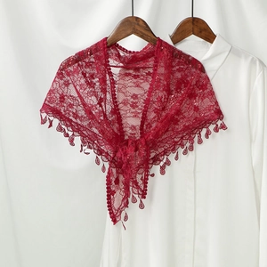Detail of red lace shawl featuring intricate floral patterns and drop-shaped fringe tassels