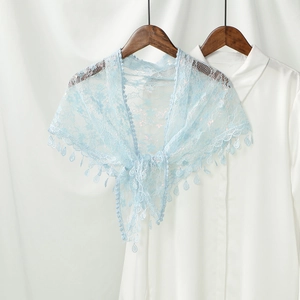 Close-up of light blue floral lace shawl with delicate tassels on a white shirt