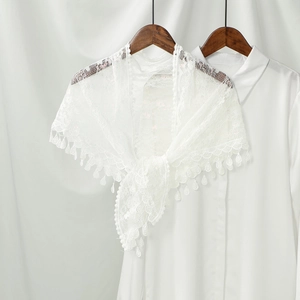 Close-up of elegant white lace shawl with delicate crochet patterns and tassel fringe detail