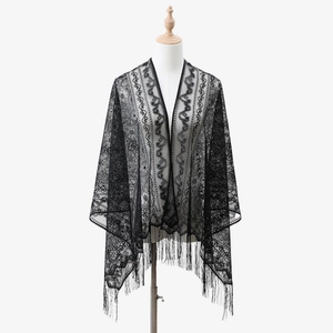 Dettaglio dello scialle in pizzo nero con trama floreale traforata e lunghe frange