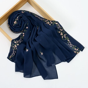 Detail of navy blue chiffon scarf with delicate pink floral embroidery and sheer texture