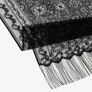 Dettaglio del tessuto in pizzo nero con motivi paisley floreali e frange eleganti