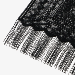 Dettaglio di pizzo floreale nero con lunghe frange e nappe dal design elegante