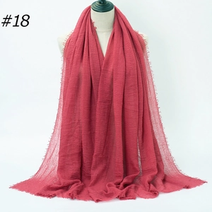 Detail of red pleated bubble gauze hijab with fine frayed edges and breathable texture