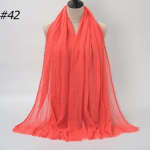 Detail of coral orange bubble chiffon scarf featuring stylish frayed edges and texture