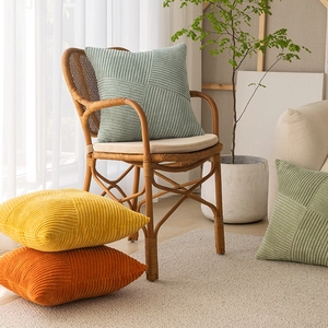 Corduroy geometric patchwork pillow cover in sage green on a stylish wicker chair