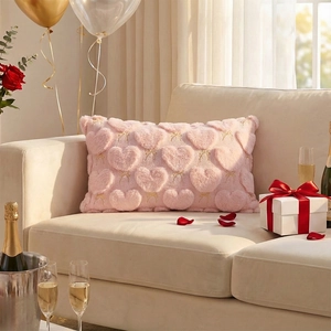 Detail of pink plush pillow featuring heart embroidery and gold bows on a white sofa