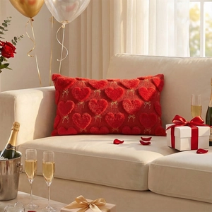 Detail of red plush heart pillow with golden bow embroidery on a cozy white sofa