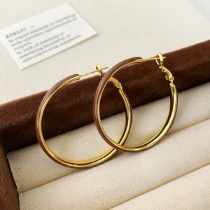 Macro detail of large gold hoop earrings with brown enamel coating in jewelry box