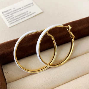 Close-up of elegant gold and white enamel hoop earrings in a luxury jewelry box