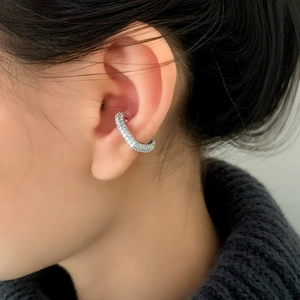 Elegant silver ear cuff with pavé-set zircon stones worn on model earlobe