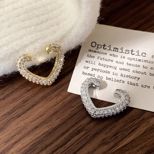 Detail of gold and silver heart ear cuffs with micro-paved cubic zirconia stones