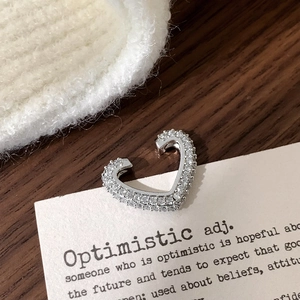 Macro shot of silver heart ear cuff with micro-pave zircons on a vintage aesthetic card