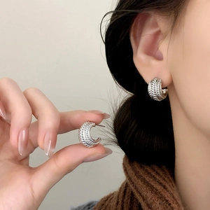 Polished silver twisted rope C-shaped hoop earrings worn for a minimalist fashion look