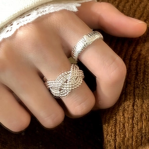 Silver braided knot ring and textured band set worn over winter knit sleeve