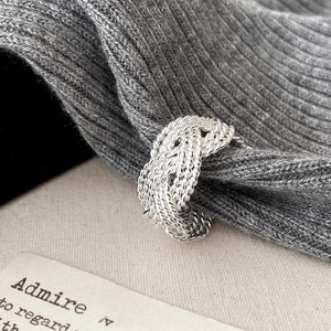 Macro shot of silver woven twist ring texture on neutral knit background