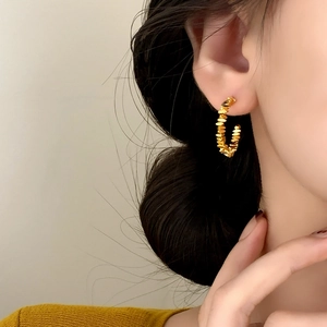 Minimalist gold textured hoop earrings with irregular geometric design worn by a model