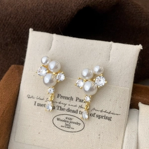 Detail of French vintage pearl earrings with zircon drops on a textured display card
