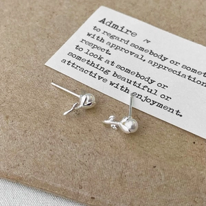 Detailed view of silver tulip earrings with pearls on a textured paper background