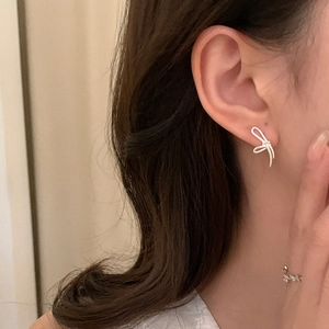 Elegant silver bow knot earrings with minimalist metallic lines on model's ear