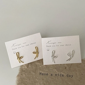 Minimalist bow knot earrings in gold and silver finish shown on a display card