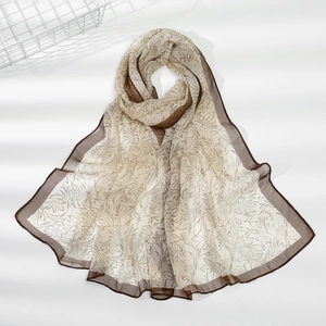 Dettaglio della sciarpa in chiffon leggero con motivo floreale marrone e bordi orlati