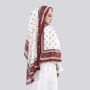 Detail of elegant chiffon hijab featuring bow patterns and a burgundy border drape