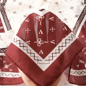 Detail of elegant chiffon scarf showing semi-transparent fabric and burgundy bow patterns