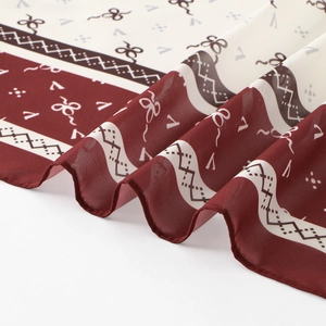 Detail of burgundy and beige chiffon scarf featuring bow prints and fine stitched edges