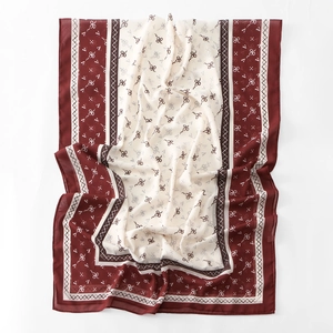 Close-up of chiffon scarf with bow patterns, burgundy and beige two-tone detail