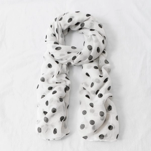 Detailed texture of white voile scarf with black polka dots featuring soft draping fabric