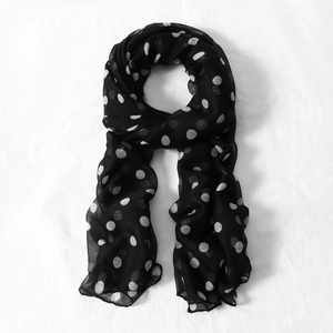 Detailed view of lightweight black voile scarf featuring classic white polka dots texture