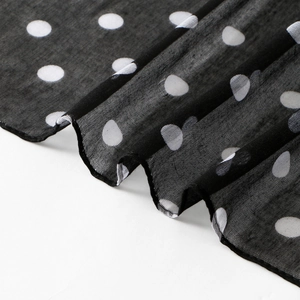 Lightweight black voile scarf with white polka dots shown in a draped elegant style