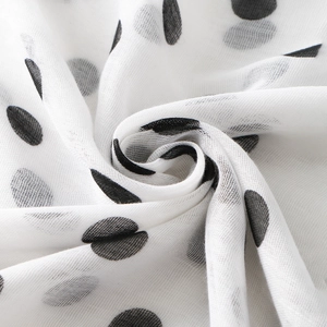 Detailed macro view of white voile scarf fabric with black polka dot print pattern