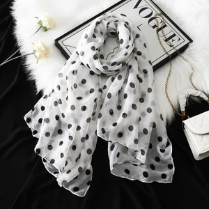 Detailed close-up of soft white voile scarf with large black polka dots and fine stitching